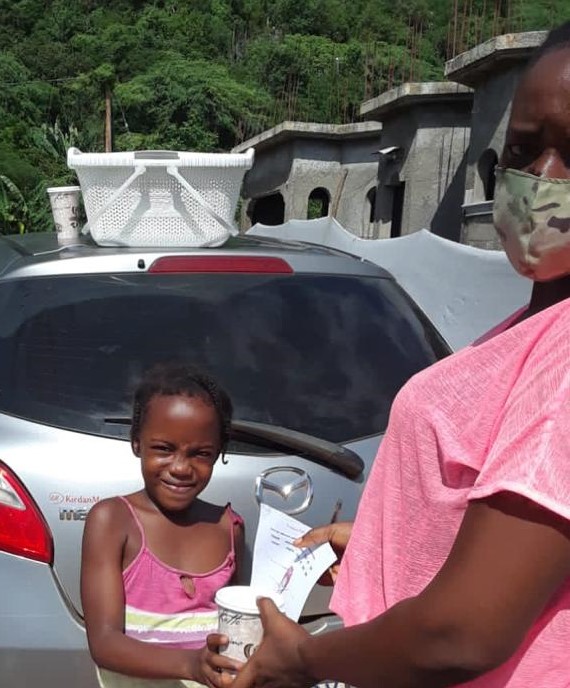 Nardia Blake-Chamberlain, guidance counsellor of Rest Primary and Infant School hands a student her worksheet and also her meal for the day. Photograph by Mike Wright